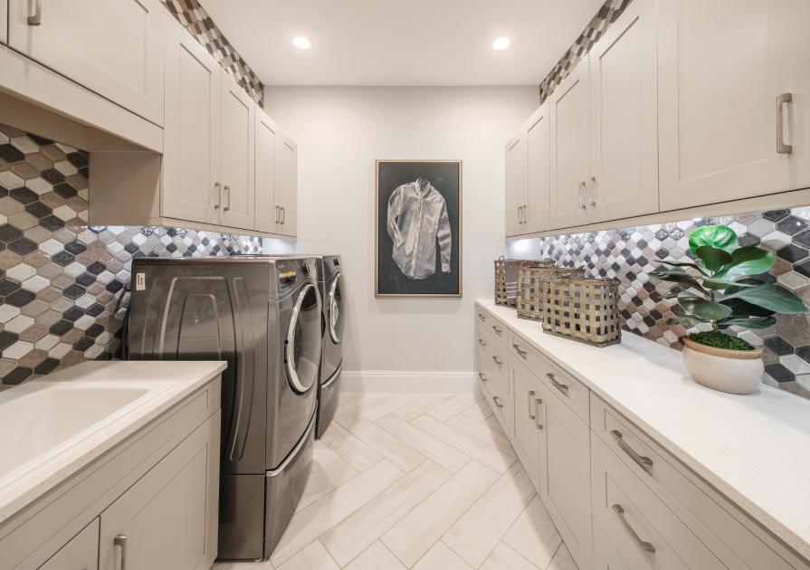 An enhanced laundry room includes upper and lower cabinets for storage and sink