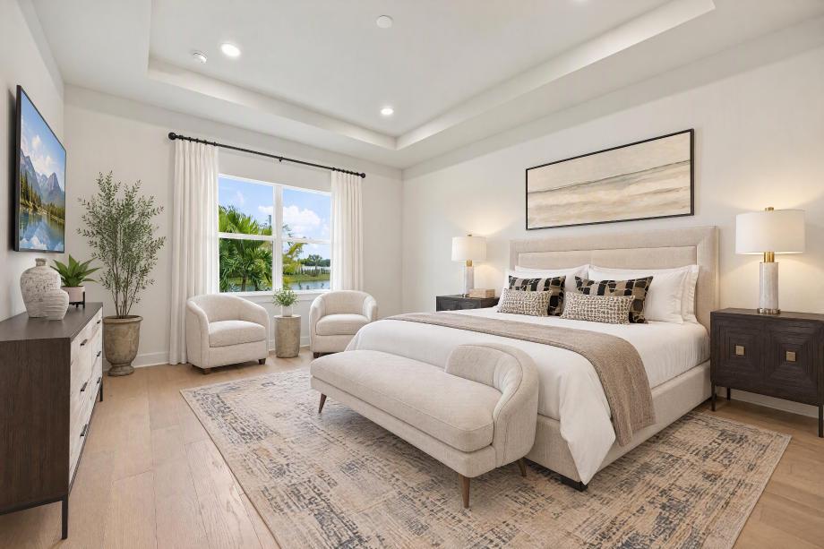 Elegant primary bedroom suite with tray ceiling and inviting sitting area