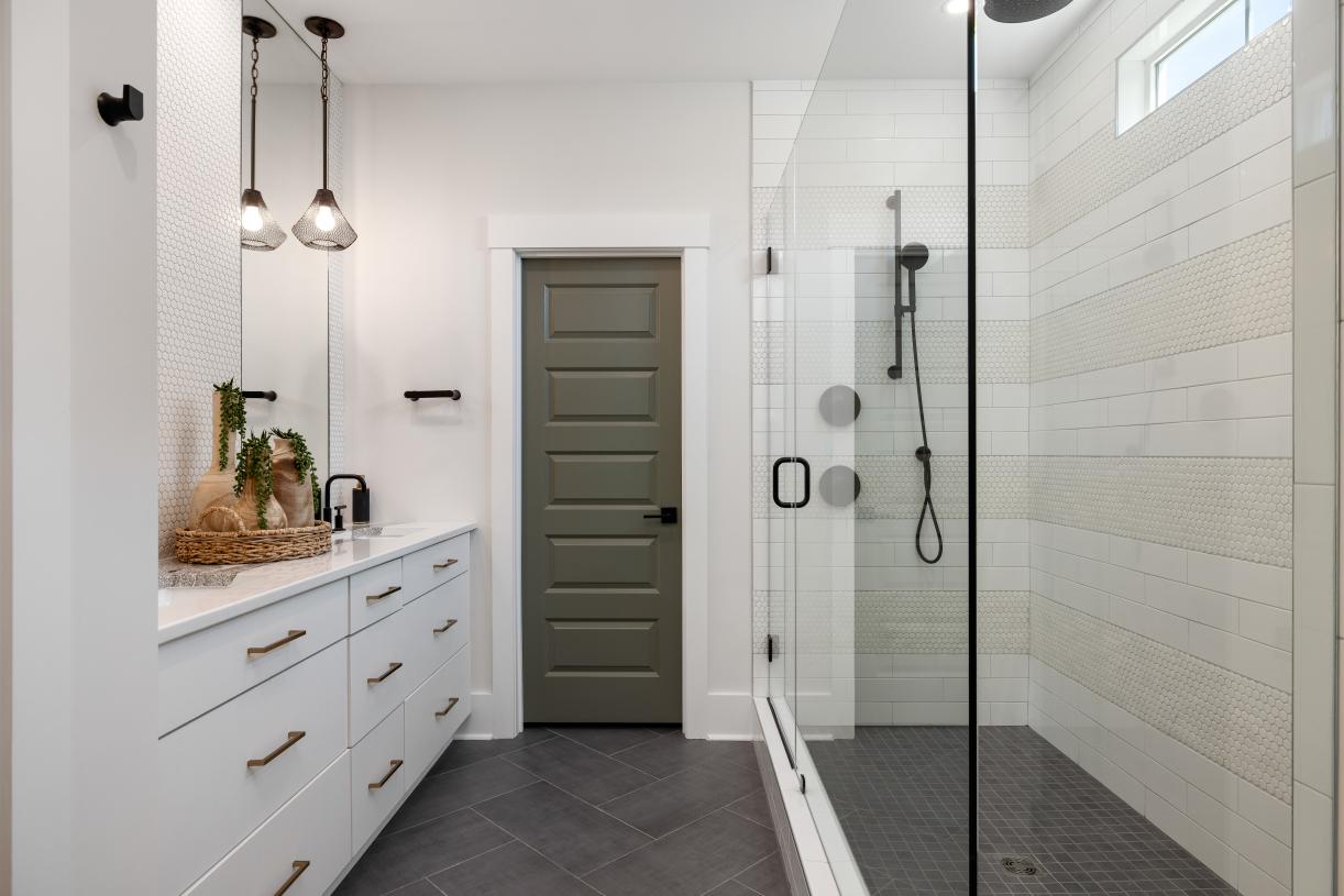 Luxury primary bathroom featuring dual vanities, glass-enclosed shower, and a private water closet