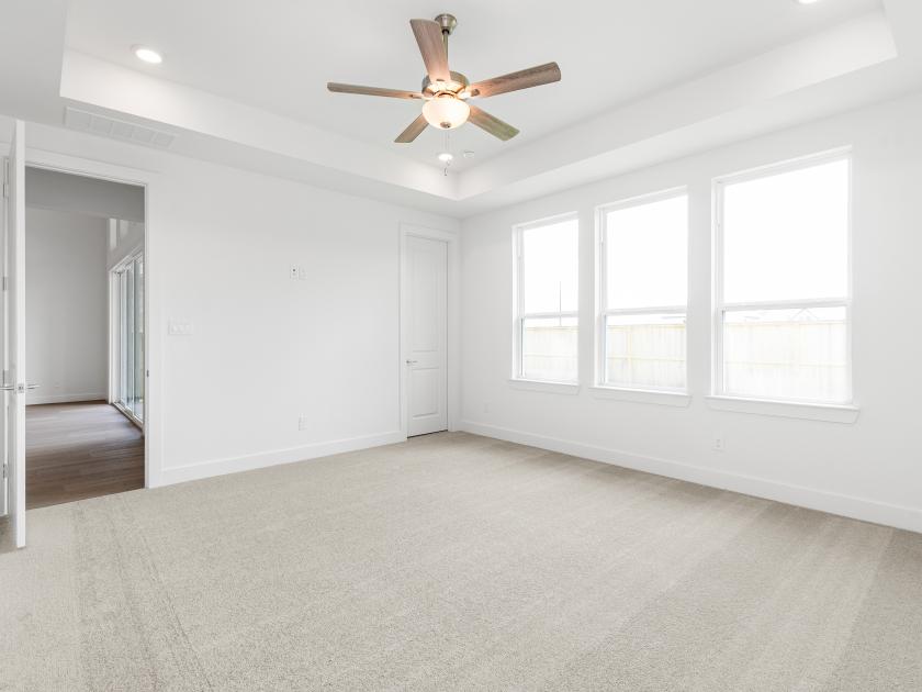 Primary bedroom suite with ample natural light and tray ceilings