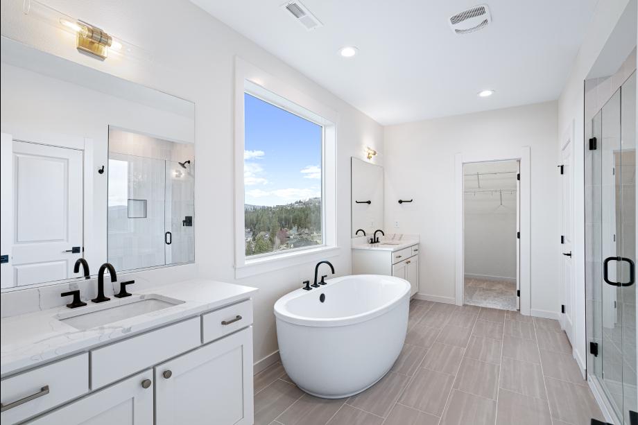 Primary bathroom features separate vanities and a freestanding tub