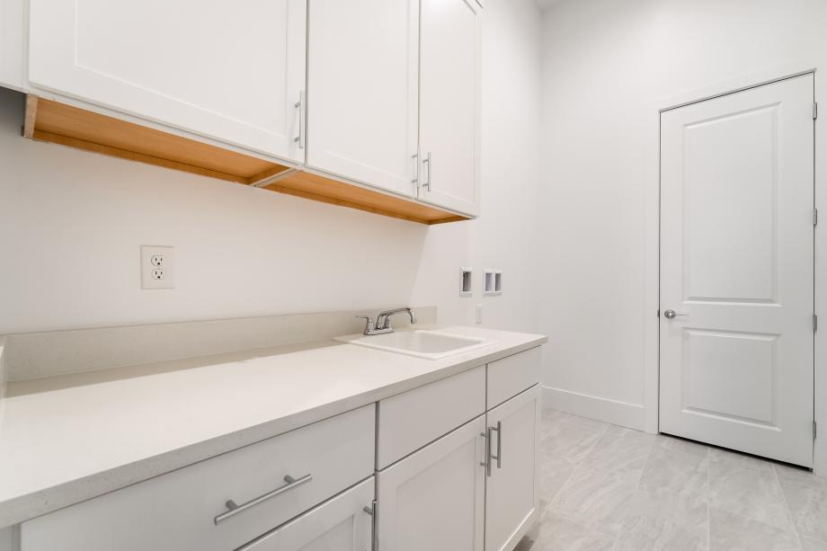 Large laundry room with sink and cabinets and walk-in linen closet