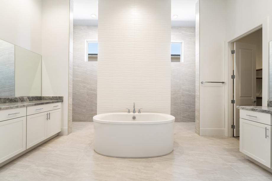 Luxe primary bath with oversized shower, separate dual vanities, and soaking tub