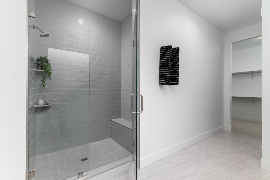 Elegant primary bath highlighted by a fully tiled shower with a built-in bench
