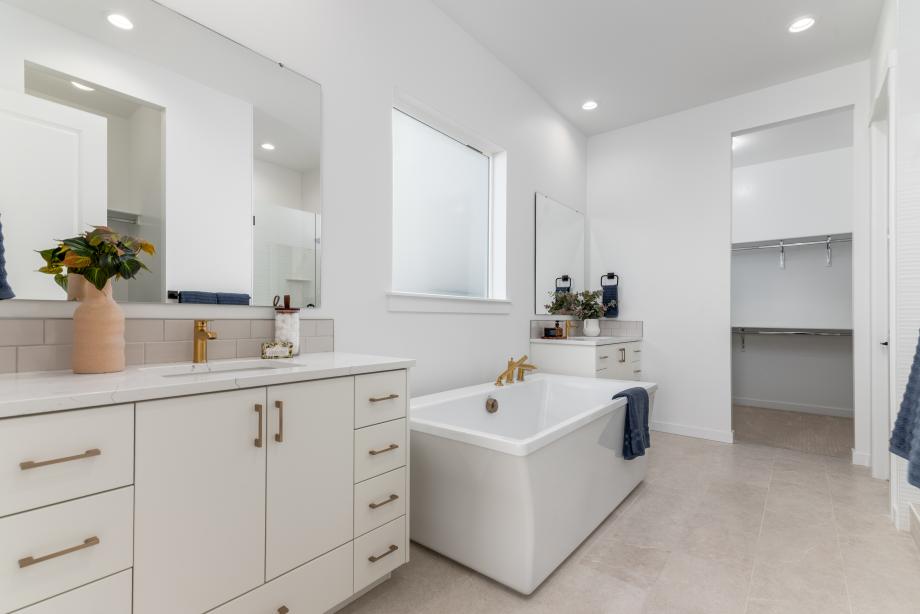 Luxurious primary bath featuring dual vanities, a soaking tub, and a spacious shower
