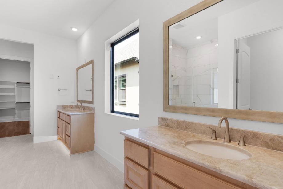 Luxurious bath featuring dual vanities and a large shower with a seat