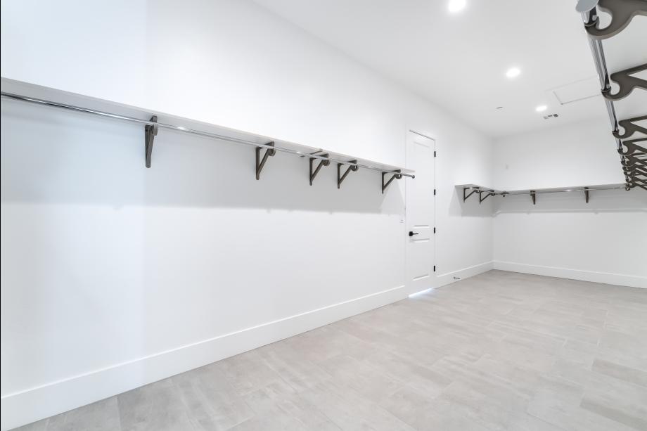 Large walk-in primary closet with separate door to laundry