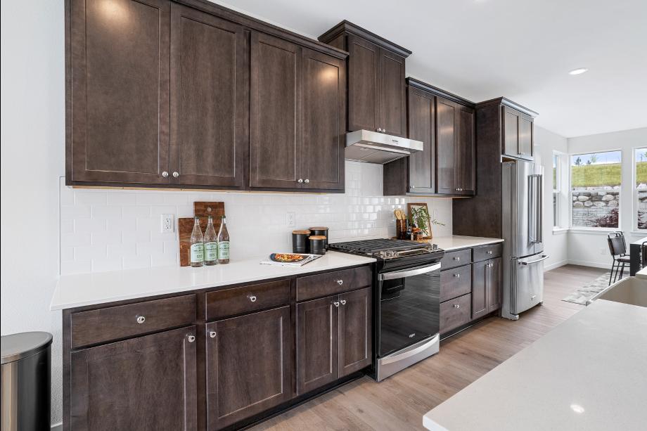 Stained shaker cabinets are complimented by white quartz countertops and tiled backsplash