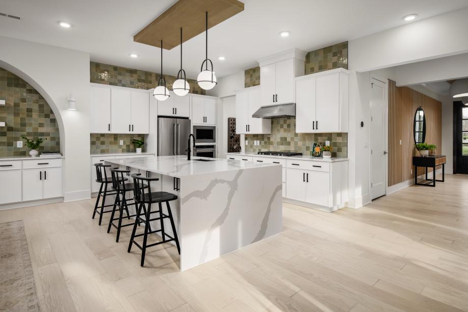 Open-concept kitchen featuring a sleek waterfall island and high-end appliances