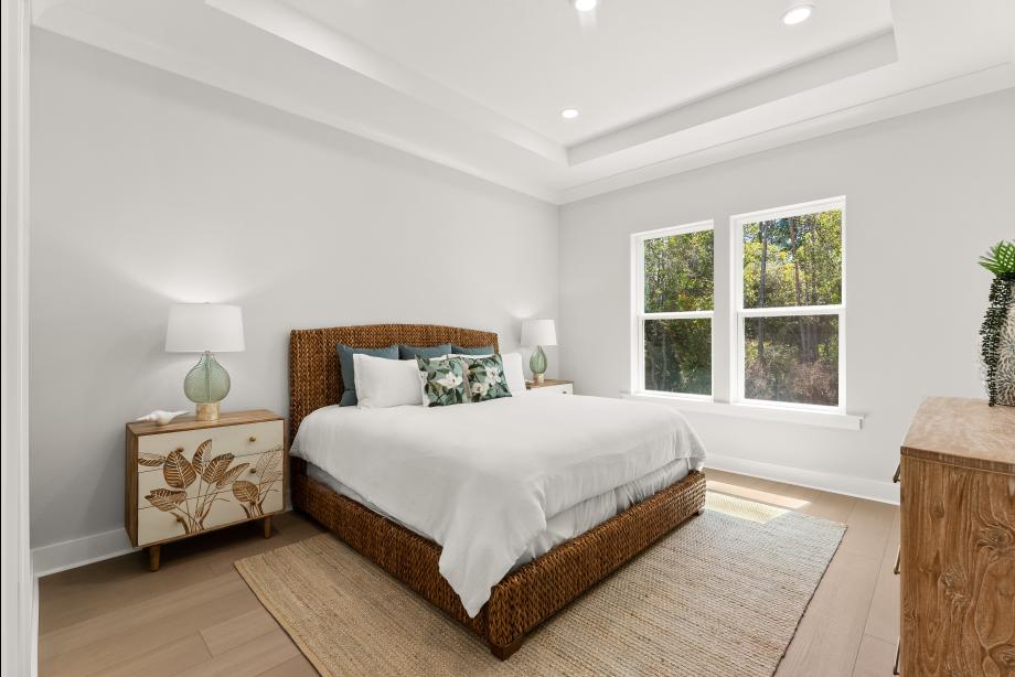 Elegant primary bedroom suite with tray ceilings and abundant natural light