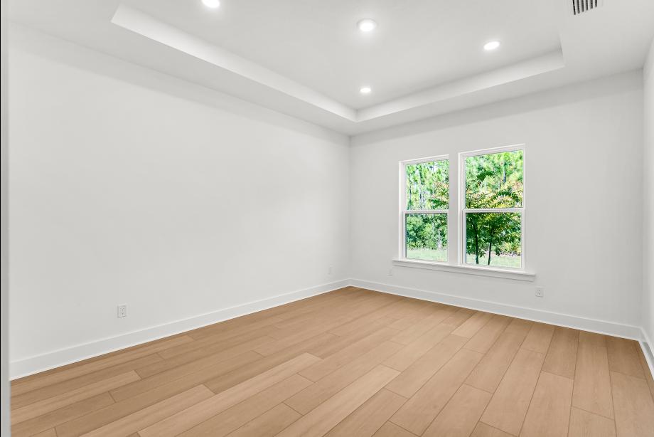 Large primary bedroom suite with tray ceilings and ample natural light