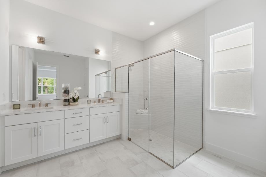 Luxurious primary baths with dual-sink vanities and glass-enclosed showers