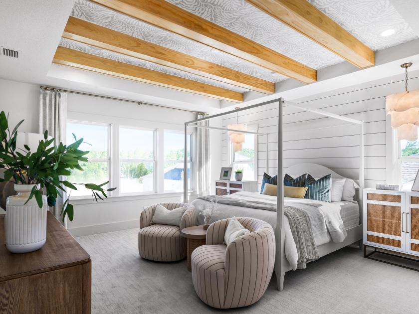Beautiful primary bedroom suite with box beams, a seating area, and natural lighting