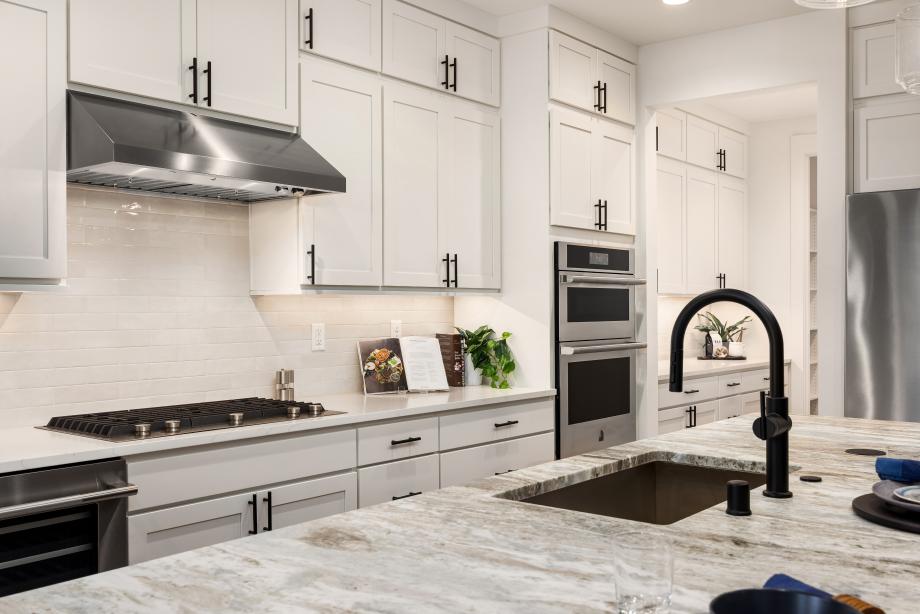 White shaker cabinets are accented by black fixtures and cabinet hardware