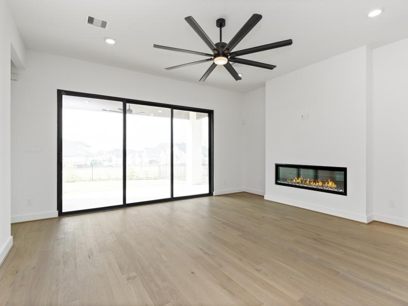 Great room with cozy fireplace and set against a wall of sliding doors that lead to a covered patio