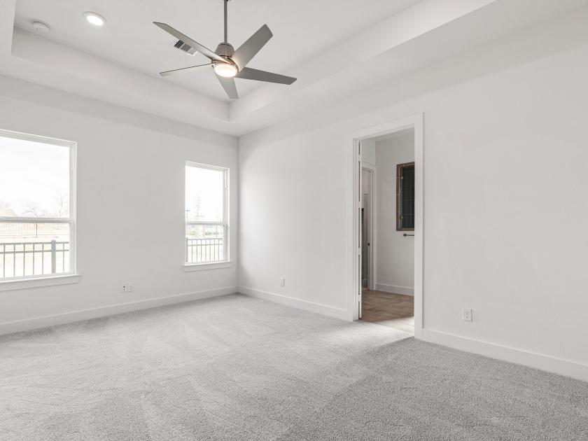 Spacious primary bedroom with tray ceiling and tranquil backyard views