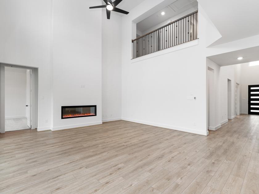 Foyer leads to open-concept great room, featuring two-story ceiling heights and cozy fireplace