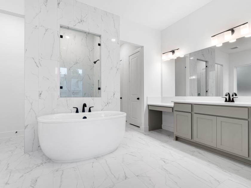 Spa-inspired primary bathroom with dual vanities, freestanding soaking tub and oversized shower